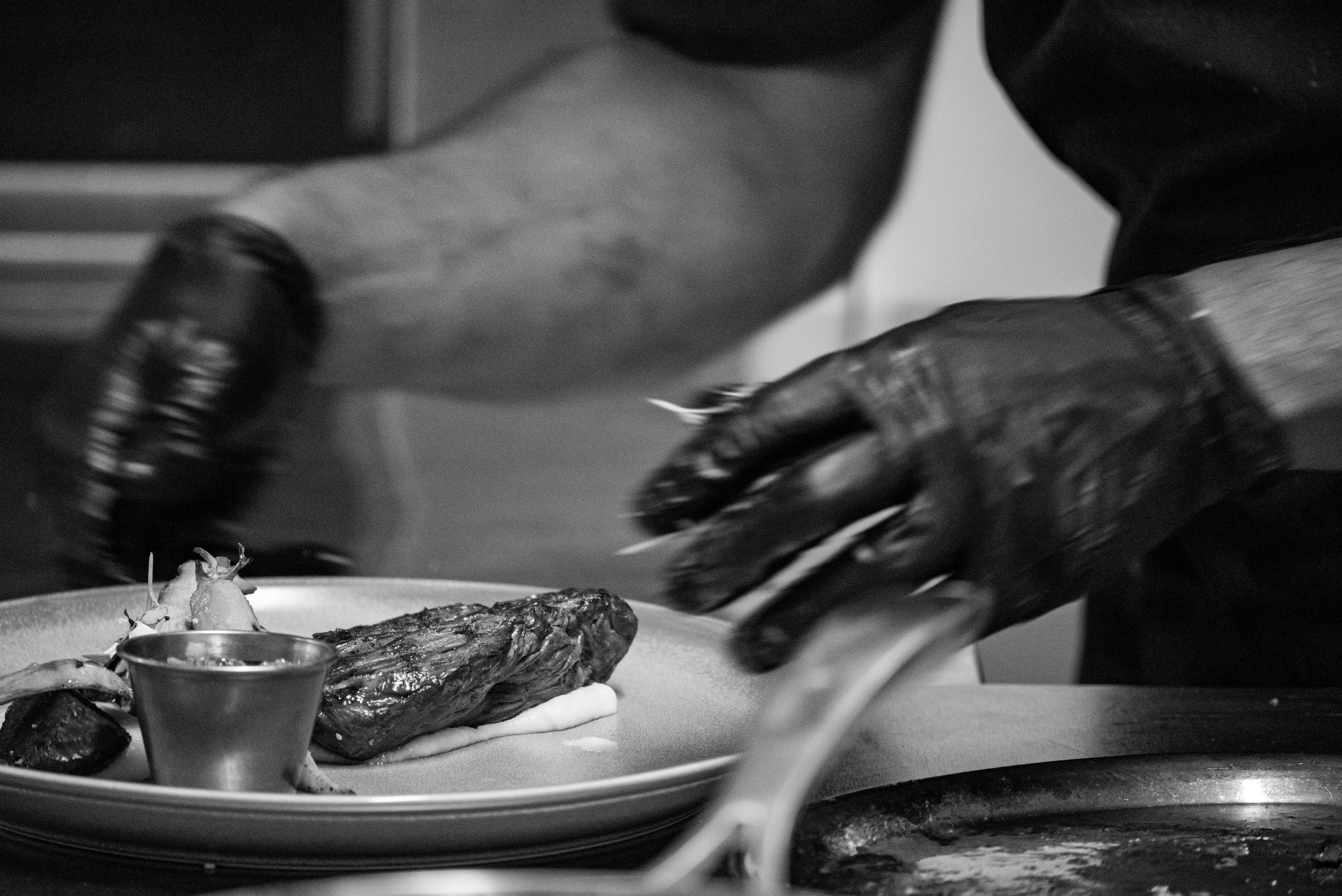 Vakmanschap in beeld: chef-kok met handschoenen aan het werk in een professionele keuken.